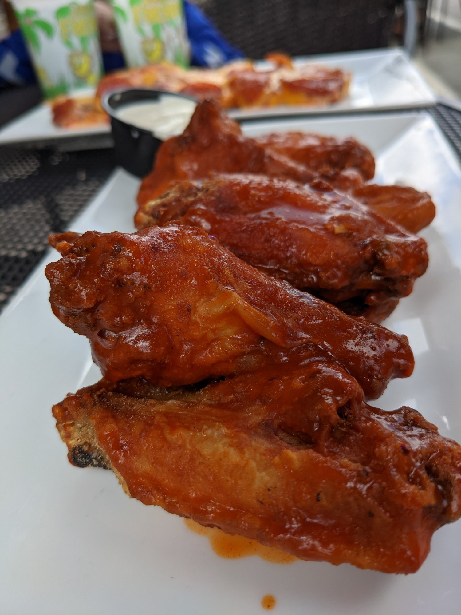 Close-up of glazed buffalo wings on a white plate outdoors in Nashua, NH